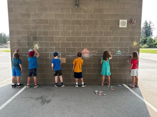 Six young students drawing colorful chalk art on an outdoor wall at Cottage Lake